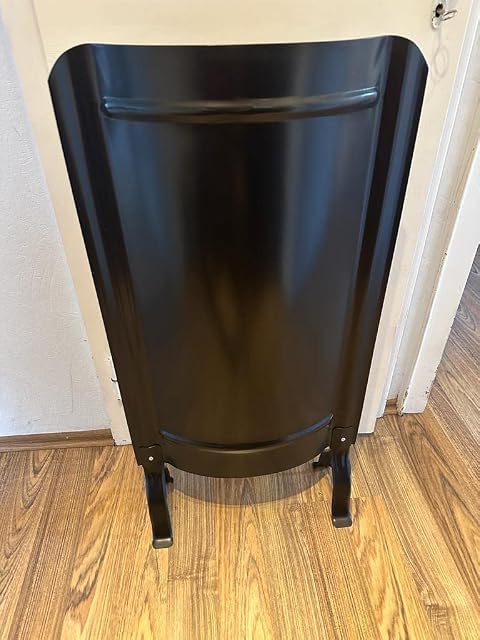 A plain black smooth stove screen standing on feet, 91 by 46 centimetres